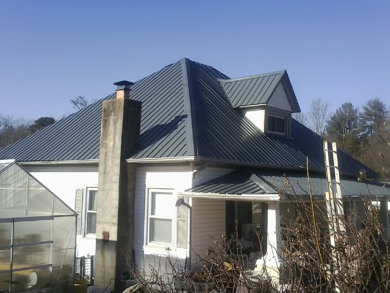 Dark blue standing seam metal roof on a white farmhouse with dormer — Slate & Tile Roof Repair by Roofing Brothers in Pahrump