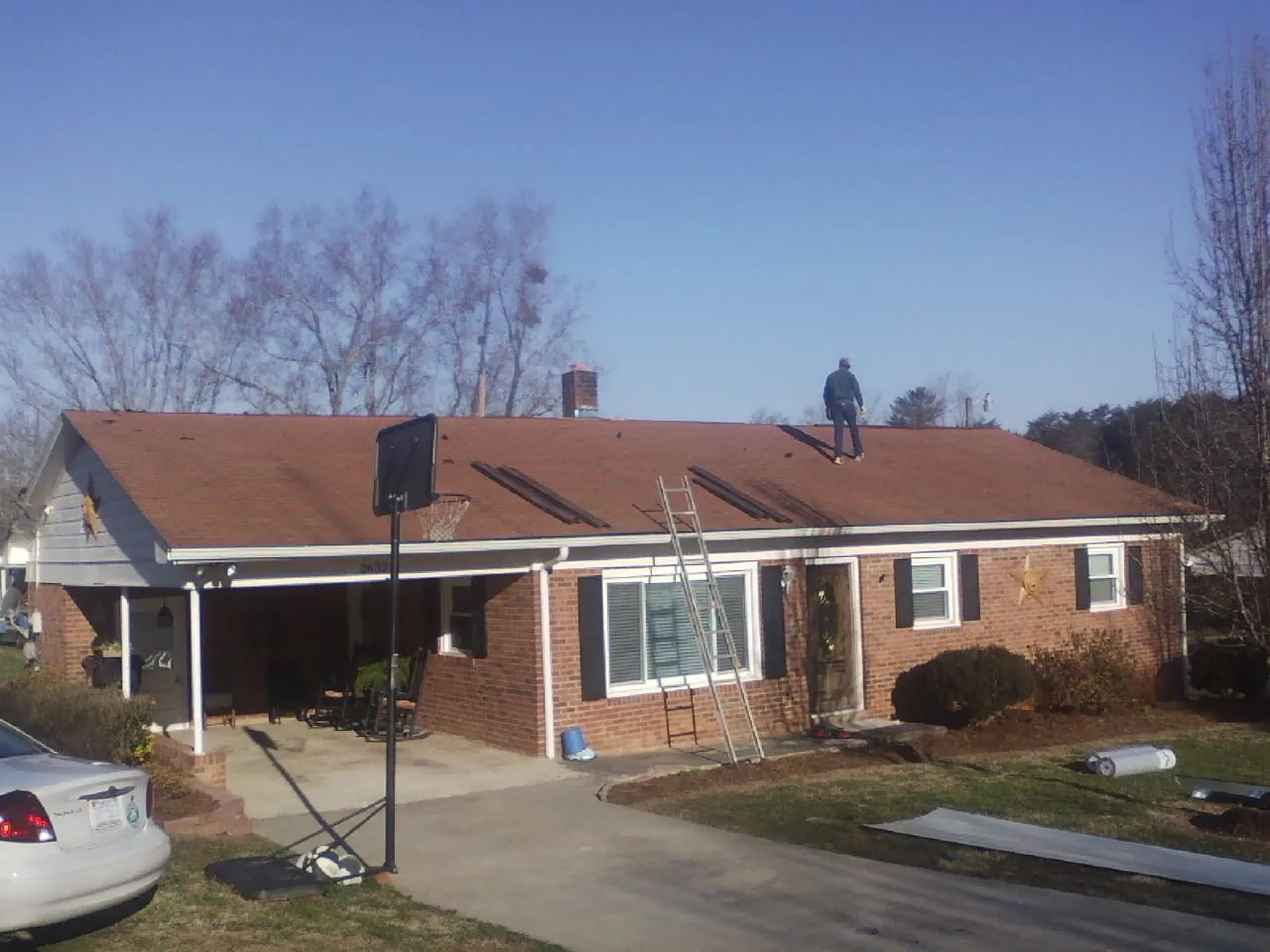 Roofer stripping a shingle roof on a brick ranch before metal panels in Pahrump