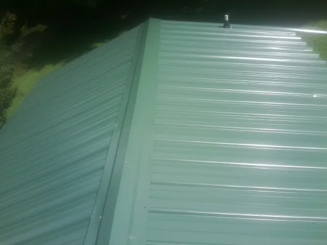 New green metal panels meeting at the ridge of a roof — Flat Roof Repair work by our crew in Pahrump