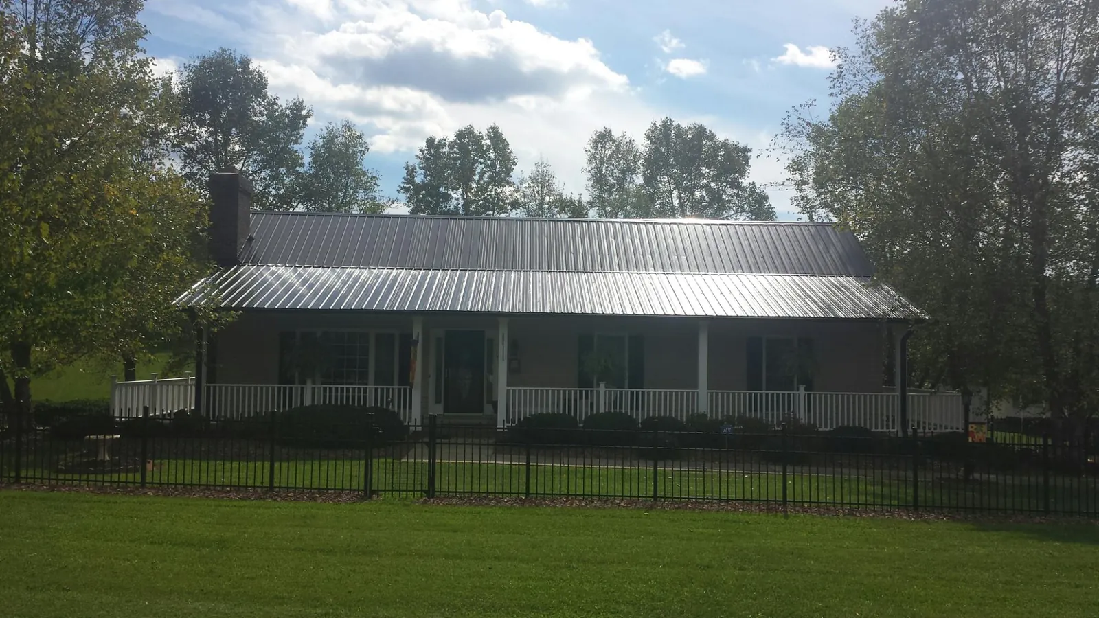 Gray metal roof on a brick ranch with a full width front porch — Gutter Guard Installation work by our crew in Pahrump