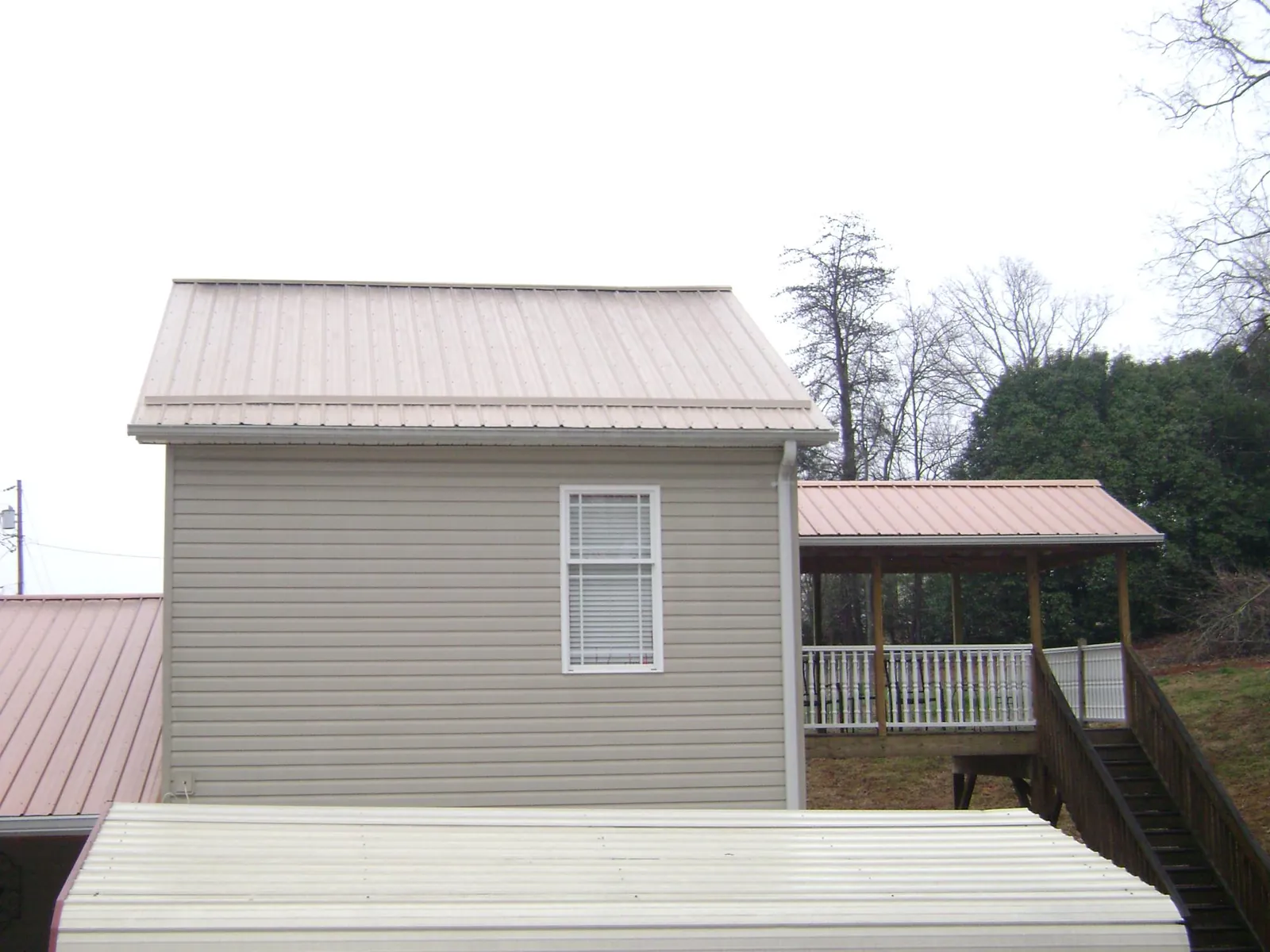Tan metal roofs on a two story addition and attached porch, from a Roof Replacement job in Pahrump