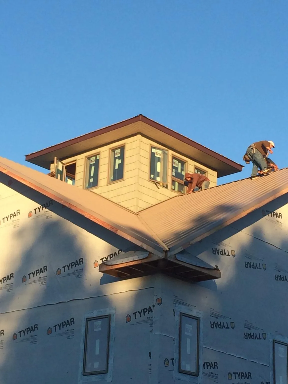 Roofers working around a rooftop cupola on a new metal roof at sunset — Roof Waterproofing in Pahrump by Roofing Brothers